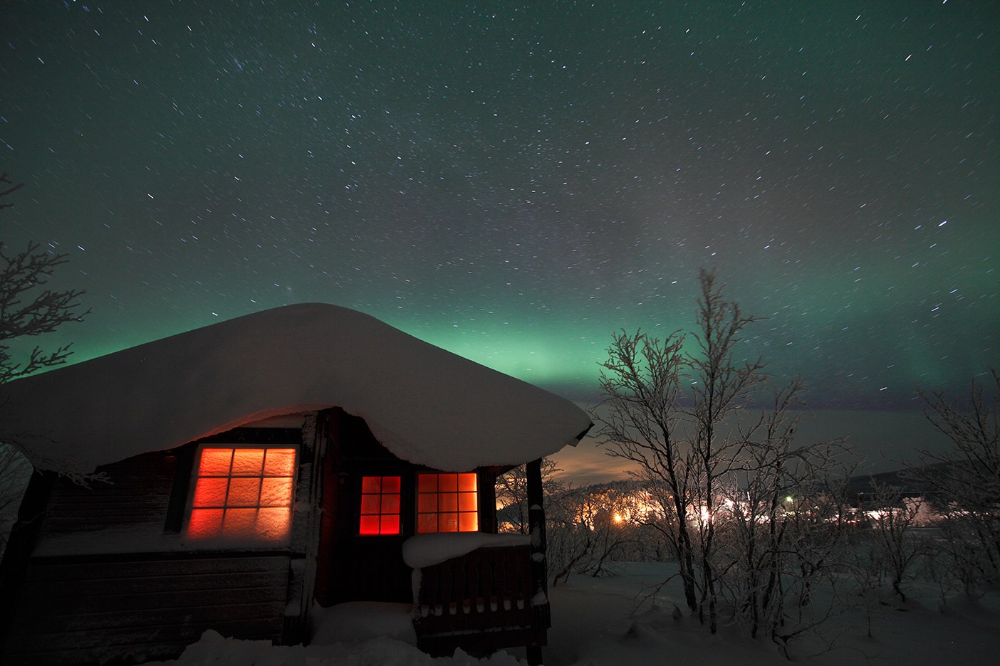 The log cabin with lit windows under the northern lights