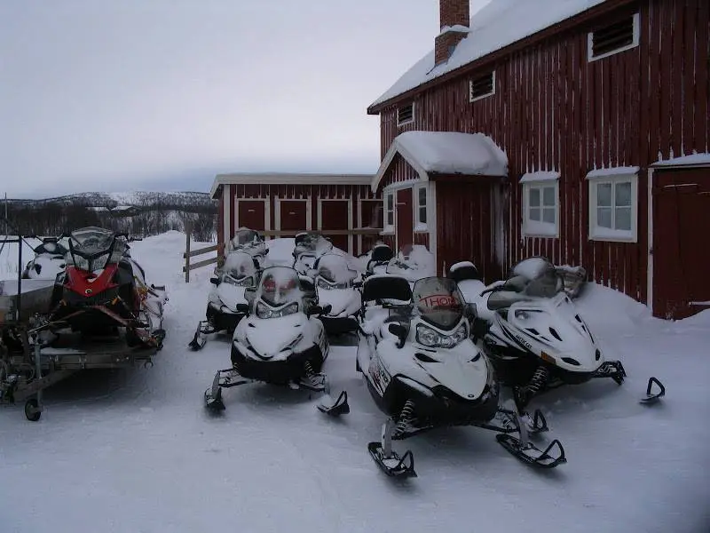 Snowmobiles in front of the red houses